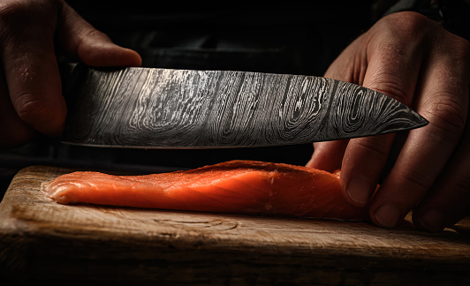 Sushi chef hands cuts raw salmon with knife on wooden table for japanese sashimi. Professional cook preparing fresh orange fish trout closeup