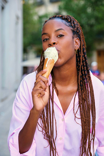 Cuban young woman eating a mint chocolate chip ice cream in summer.