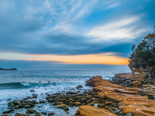 istock Sunrise, rocks and surfers at the Seaside 1987190629
