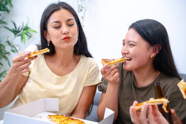 istock Women enjoy pizza together, sharing smiles. 1987209005