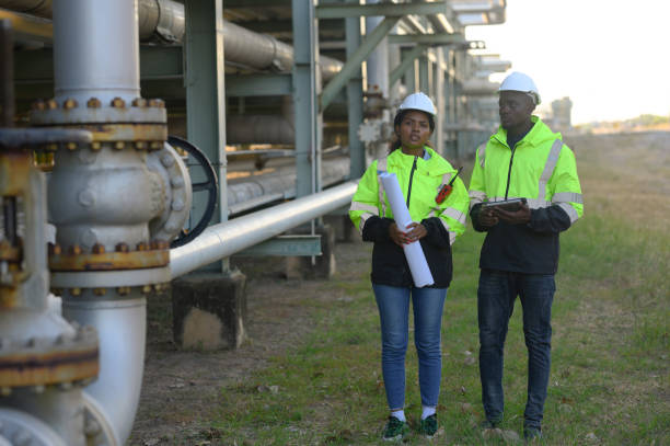 istock Male and female engineers check the drawing system inspection with the real pipe system of the new construction project, engine engineer, Sysetm cooling machine, compared to drawing design. 1987212759