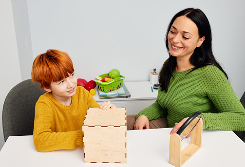 Child development specialist woman working with child with autism spectrum disorder. Play-based therapy