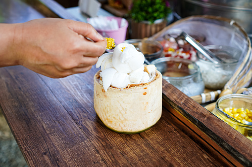 Picture of people adding Golden Beans topping to coconut milk ice cream at a street food market, Chiang Mai, Thailand.