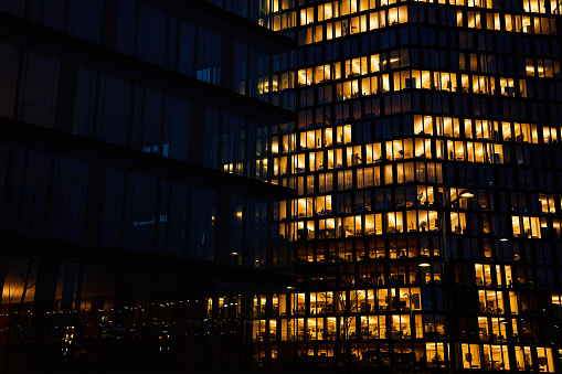 Office building exterior with glowing lights in windows at night city. Vienna city downtown district with skyscraper facades. Night city panorama. Working late at corporation