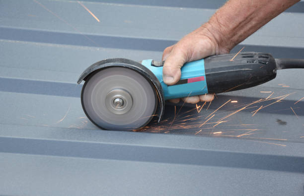 istock Roofer constuctor is cutting with a power angle grinder a corrugated metal roofing sheet. Cutting metal roof tile. 1987228904