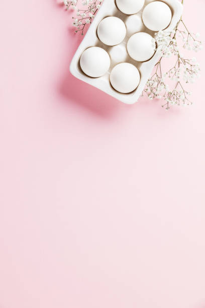 istock White eggs  in white ceramic holder and flowers on pink background 1987239234