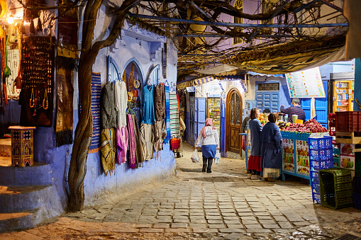 Street with shops at night in the city of Chefchaouen, Morocco, North Africa.