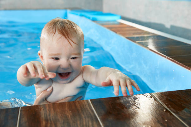 istock Little baby learning to swim in pool with trainer 1987244132