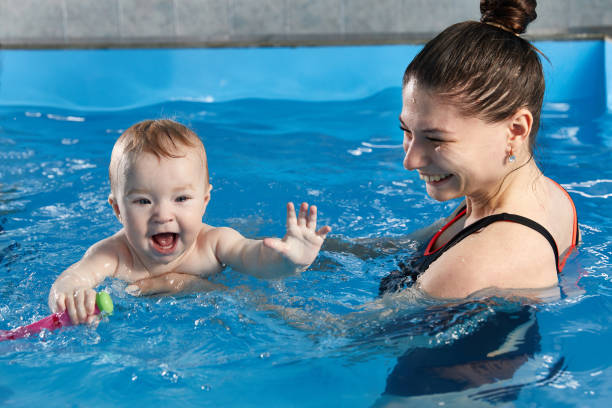 istock Little baby learning to swim in pool with teacher 1987244133