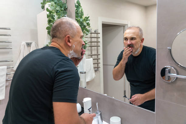istock Man shaving with razor using foam in bathroom in the morning 1987249610
