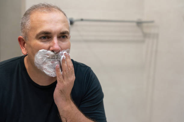 istock Middle aged handsome man shaving his beard in bathroom 1987249789