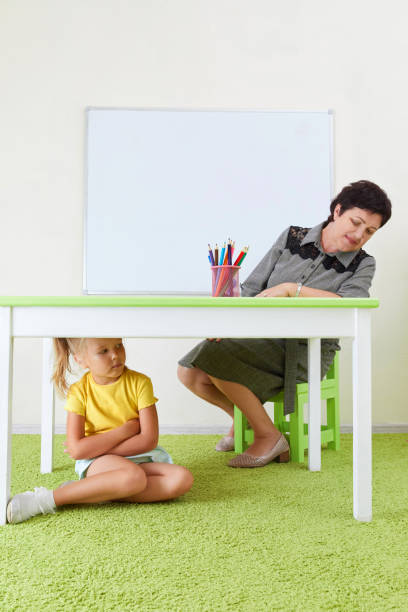 Scared Girl Hiding Under Table sitting on a floor
