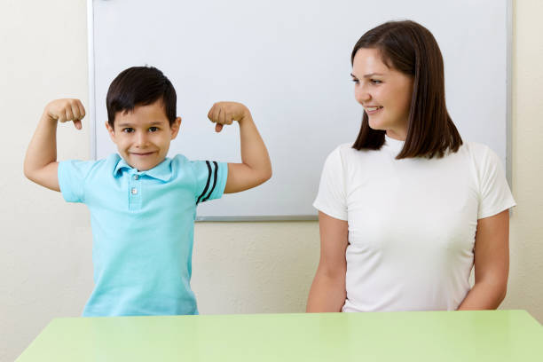istock Boy is showing his arm muscles to his teacher 1987253099