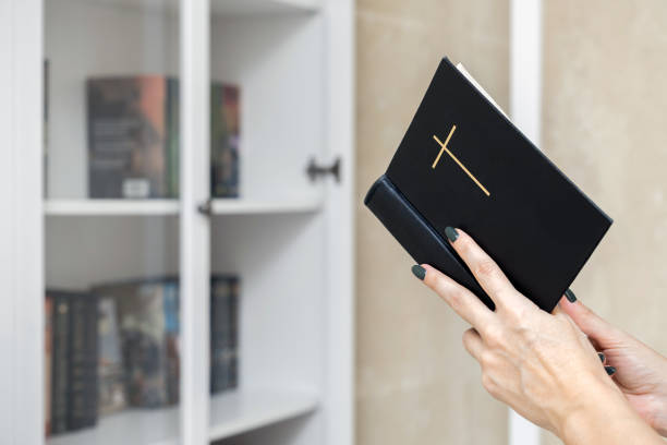 woman reading the bible standing near a bookcase. bible in hands