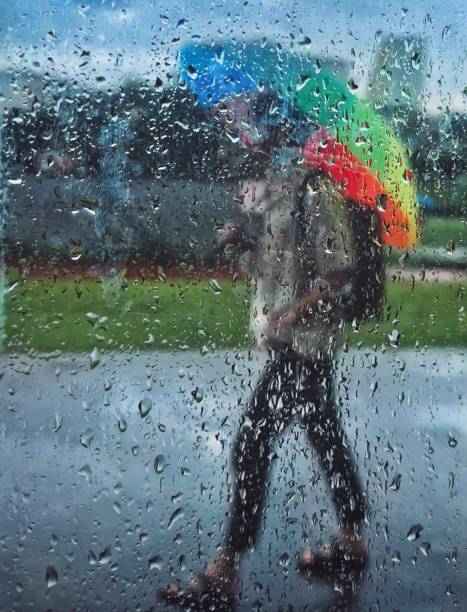 Young woman walking in rain holding a colorful umbrella