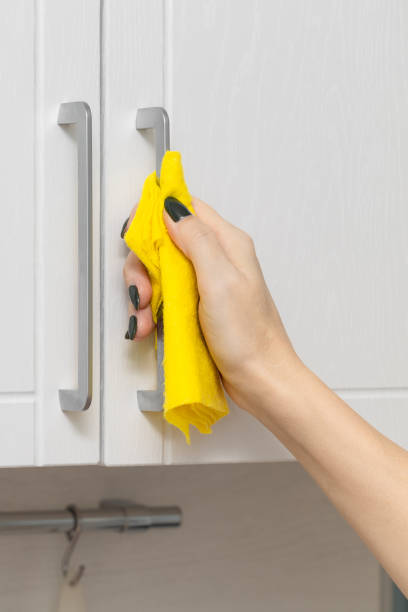 istock a woman's hand wipes the handle of a kitchen cabinet with a rag 1987280731