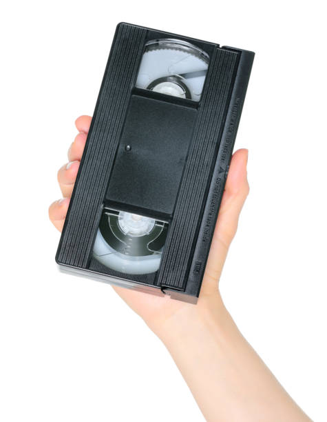 istock Woman hand holds a retro old analog video cassette, isolated on white background, retro things concept 1987281836