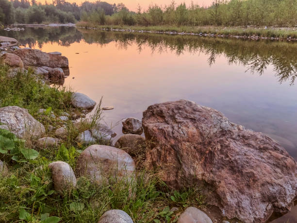 Beautiful summer landscape with river and rocks on the shore at sunset