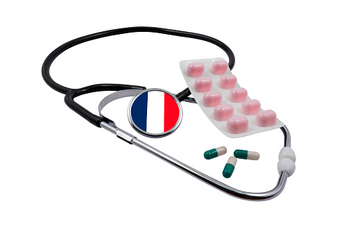 Medical stethoscope with a head in the shape of a French flag and pills isolated on a white background. Concept of medical diagnostics and the French healthcare system