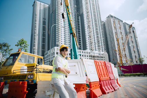 Portrait of young engineer in hardhat standing at construction site.