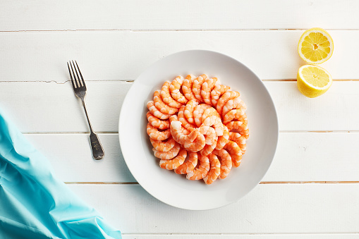 Plate, shrimp and seafood in studio on table, restaurant menu and shellfish for protein as nutrition meal. Above, dinner and raw fish for healthy food, omega 3 and lunch for brain by white background