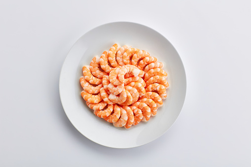 Plate, shrimp and seafood in studio for lunch, restaurant menu and shellfish for protein or nutrition. Above, dinner and raw fish for healthy food, omega 3 and lunch for brain by white background
