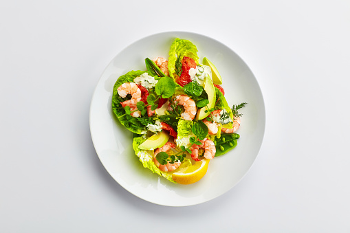 Spicy seafood salad with shrimp in white plate on wooden table