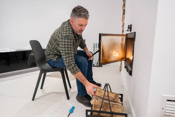 istock Caucasian man put an log into fireplace, at his home 1987296356