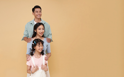 Portrait happy smiling Asian family hugging and looking isolated on nude color copy space background.