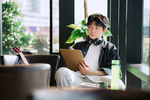 Young Asian Chinese Man Relaxing In Cafe.