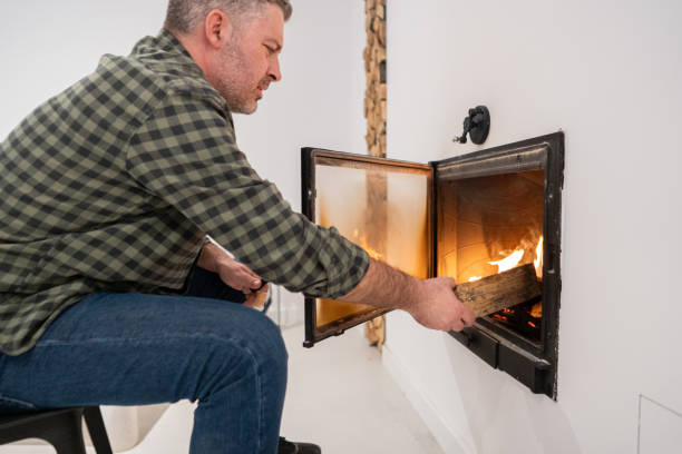 istock Caucasian man put an log into fireplace, at his home 1987303877