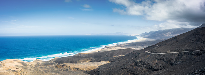 Canary Islands Cofete Beach View in the Jandia National Park. Atlantic Coast of Jandia National Park Fuerteventura Island. Hasselblad X2D stitched XPAN Crop Panorama of Playa de Cofete, Cofete Beach, bordered by the mountains of Jandia National Park in the south of Fuerteventura, Spain. Jandia National Park, Fuerteventura Island, Canary Islands, Spain - Africa.