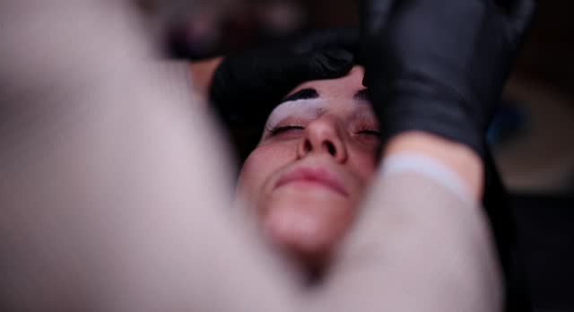 Beautician Applying Microblading Technique To Shape And Fill In A Client's Eyebrows At A Modern Beauty Salon