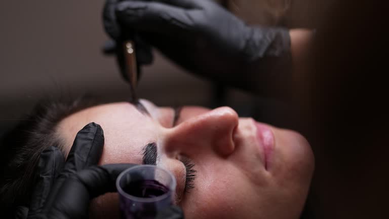 Beautician Applying Microblading Technique To Shape And Fill In A Client's Eyebrows At A Modern Beauty Salon