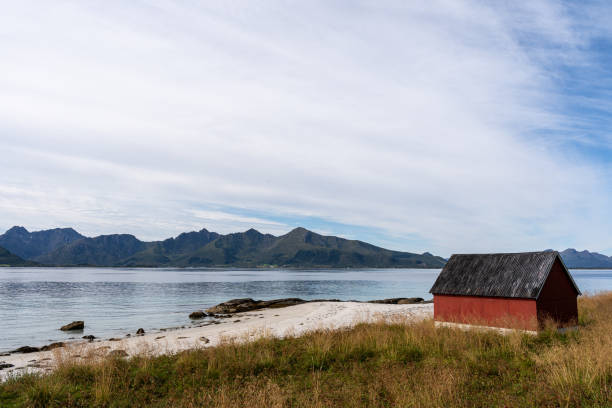 istock Charming crimson beachside shed overlooking the vast ocean, in Andoya Norway 1987343355