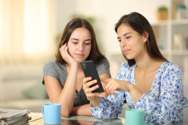 istock Serious friends checking phone at home 1987345005