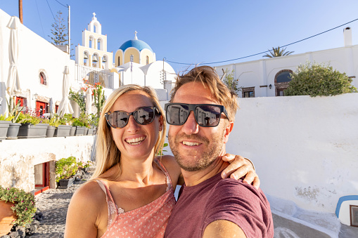Romantic escape in Santorini: A couple's selfie frames their love against the backdrop of a beautiful Greek village. Elevate your travel dreams in Europe.