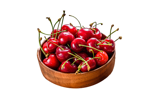 Red cherries in a wooden bowl.  Isolated on white background. Top view