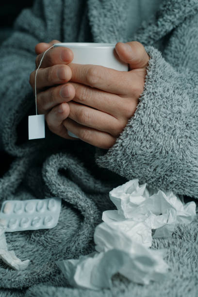 istock ill man warming himself with a cup of herbal tea 1987354238