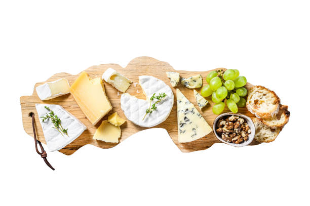 Assorted cheeses on a wooden cutting Board. Camembert, brie, Parmesan and blue cheese with grapes and walnuts.  Isolated on white background. Top view