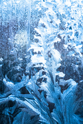 Frost patterns on frozen winter window as a symbol of Christmas wonder. In the middle of the window is a misted space for your product or lettering. Christmas or New year background.