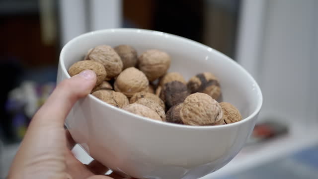 Farmer Hand Holding a Full Bowl of Harvested Walnuts. Close-up. Slow-Motion
