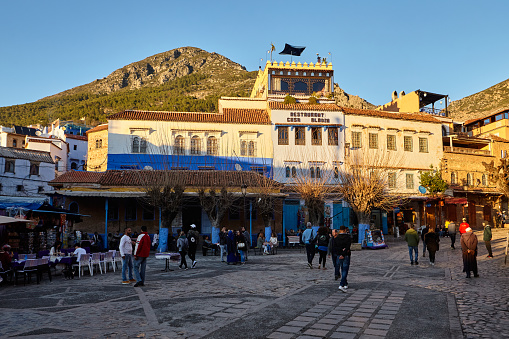 Place Outa El Hamam square with group of people at sunset in Chefchaouen, Morocco, North Africa.