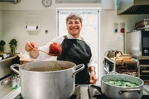 Portrait of a chef while she's preparing a vegetable soup before dinner service. She's working in a professional restaurant's kitchen.