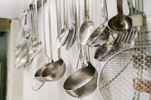 Hanging ladles in a professional restaurant's kitchen. Many ladles in a commercial kitchen.