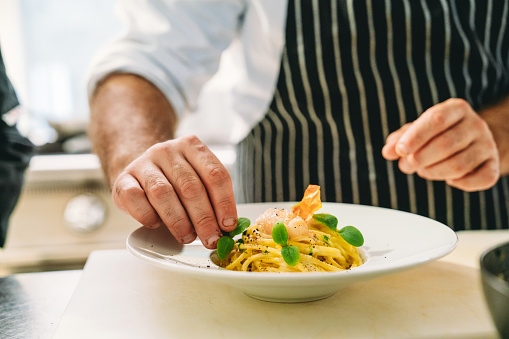 A chef is plating spaghetti. He's paying attention to details.