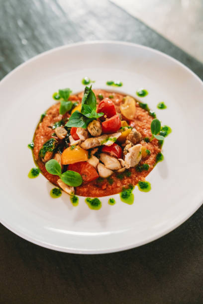 Slices of fried cod fish with sweet bell peppers on the white dish on the festive table, prepared for eating.Healthy mediterranean food concept.
