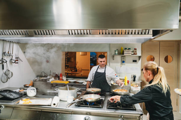 Chefs are cooking in the restaurant kitchen. Team of cooking staff preparing different dishes.