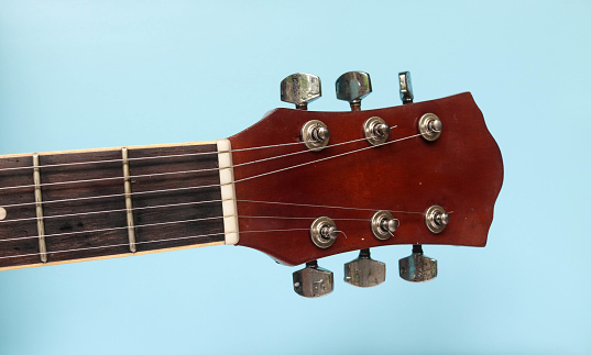 Macro image showing the bridge and the strings held up by the saddles on the body of a vintage style electric guitar.