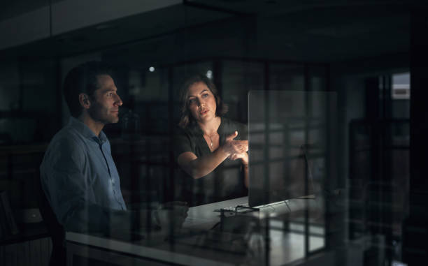 Computer, teamwork and business people planning at night, discussion or brainstorming in startup. Desktop, deadline and employees, programmers or coders in collaboration for information technology